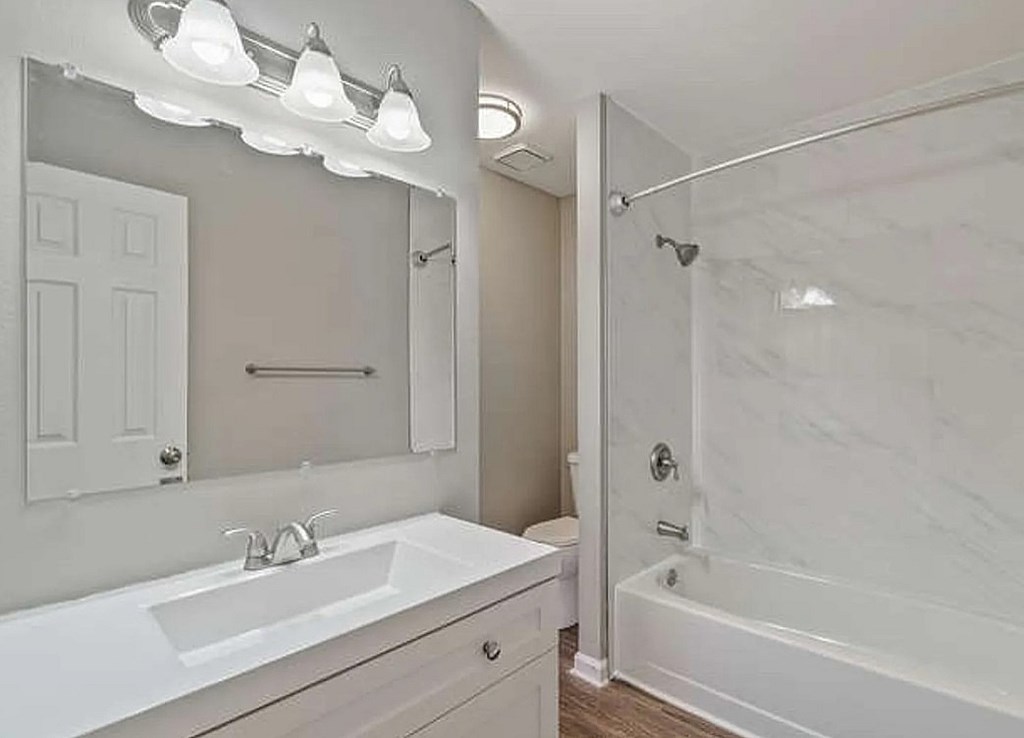 A white bathroom with a marble tub and a white sink.