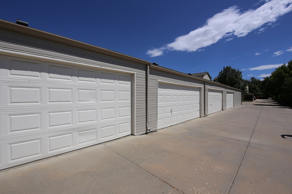 A row of white garage doors on a sunny day.