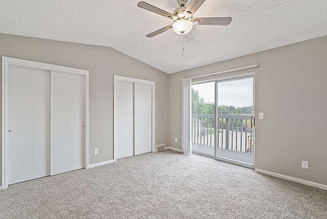 A room with a ceiling fan and carpeted floor.