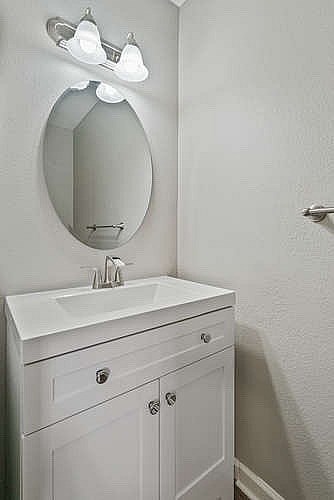 A white bathroom vanity with a round mirror and lights above it.