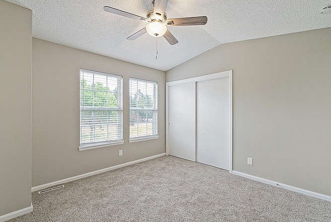 A room with a ceiling fan and two windows.