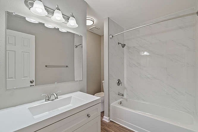 A white bathroom with a marble tub and a white sink.