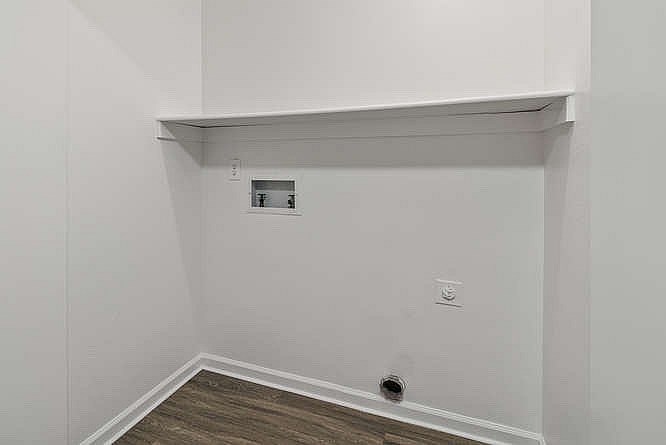A white wall with a small electrical outlet and a vent.