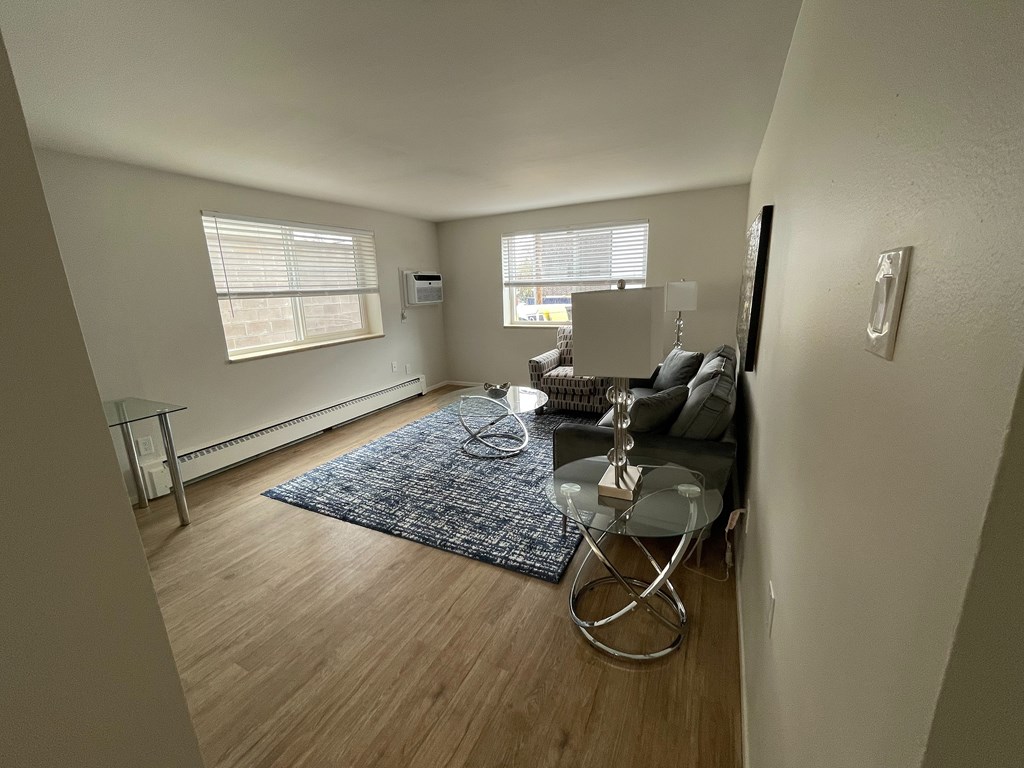 A living room with a grey sofa and a glass table.