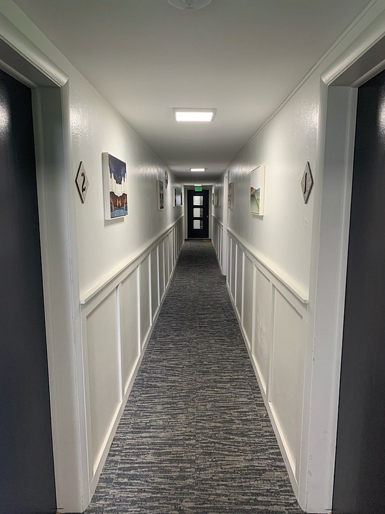 A long hallway with white trim and pictures on the wall.