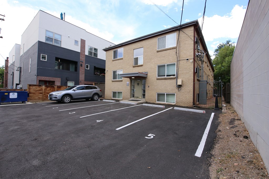 A parking lot with a car parked in it and a building in the background.