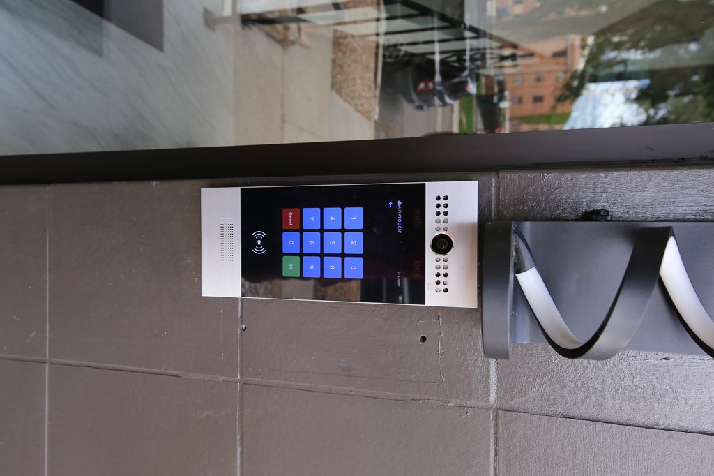 A control panel with blue and white buttons is mounted on a wall.
