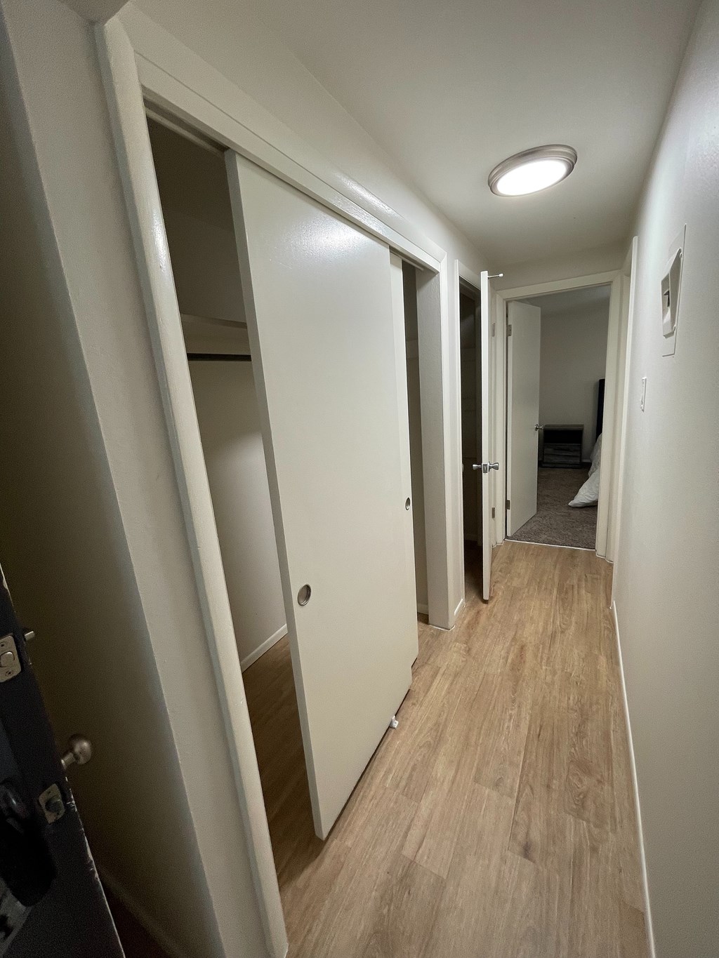 A long hallway with white walls and wood flooring.
