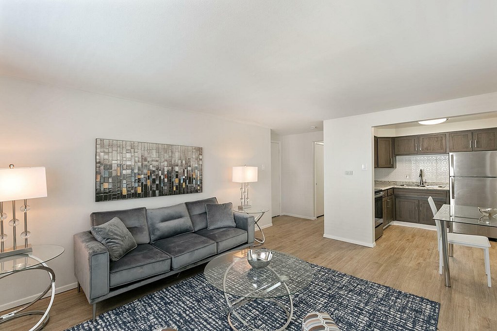 A grey couch sits in a living room with a glass table in front of it.