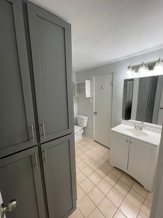 A room with white walls and wooden flooring, with a window covered by blinds.