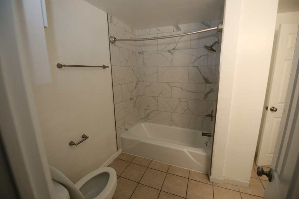 A white bathroom with a toilet, tub, and shower.