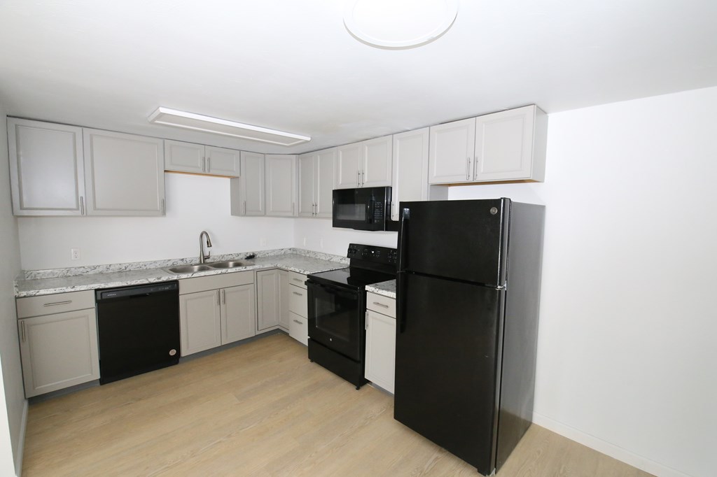 A kitchen with black appliances and white cabinets.