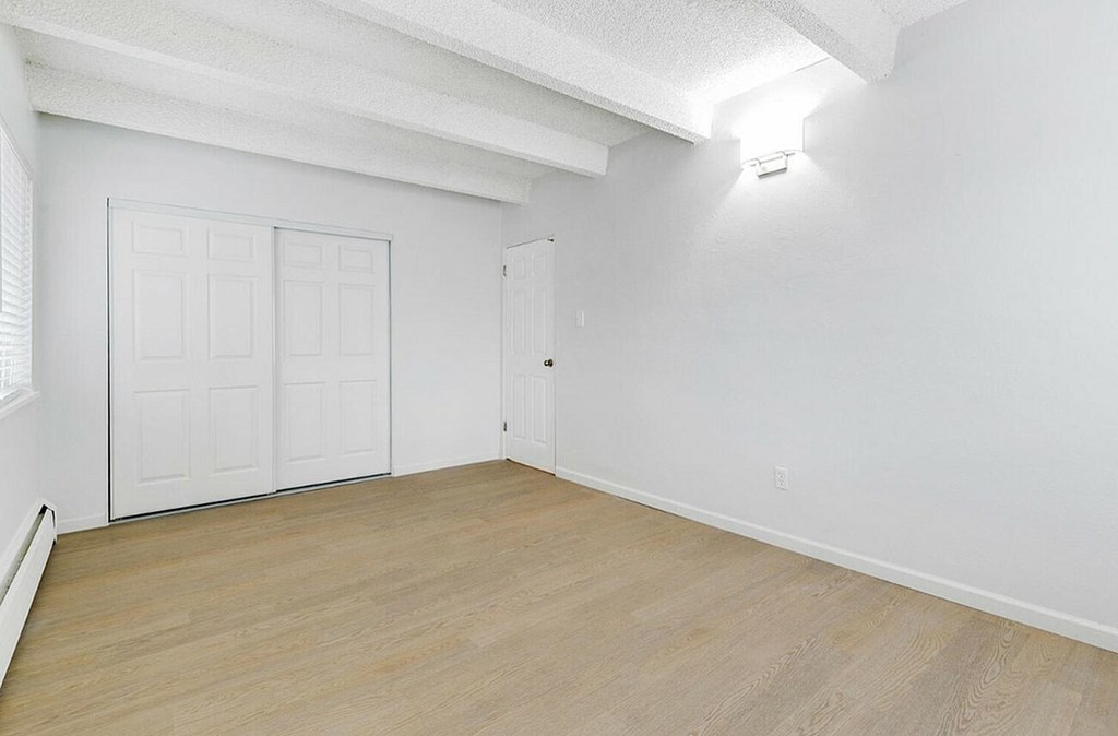 A room with a white wall and a wooden floor.