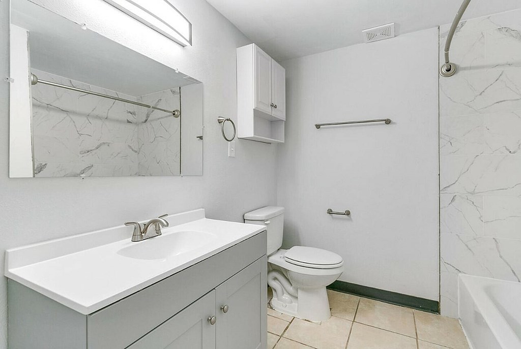 A white bathroom with a marble wall and a toilet.