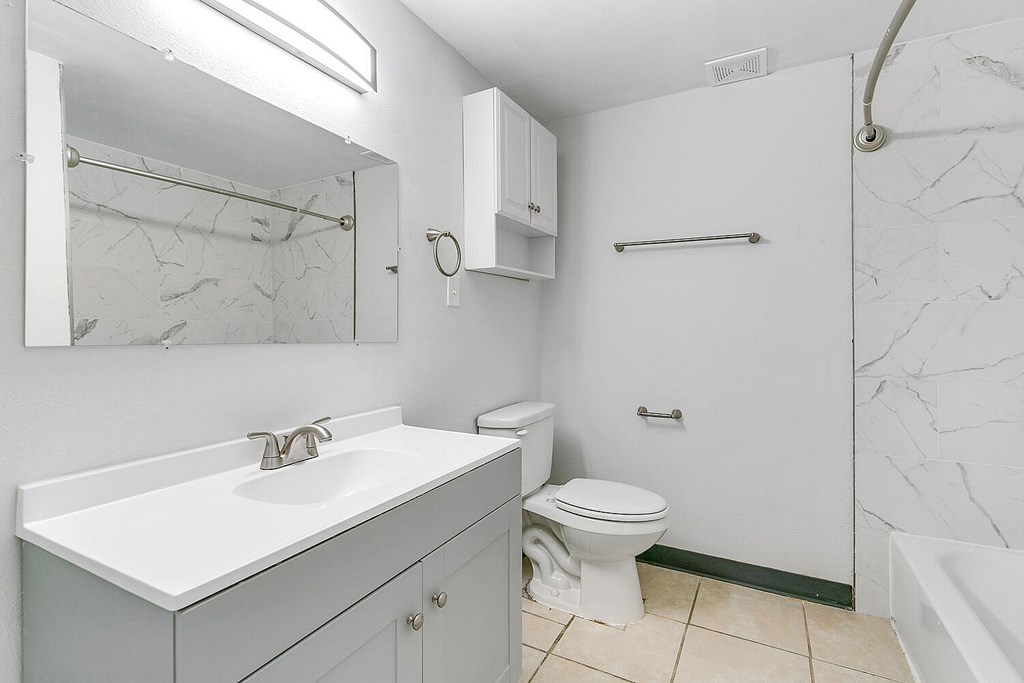 A white bathroom with a marble wall and a toilet.