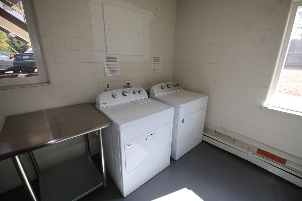 A small room with two white washing machines and a table.