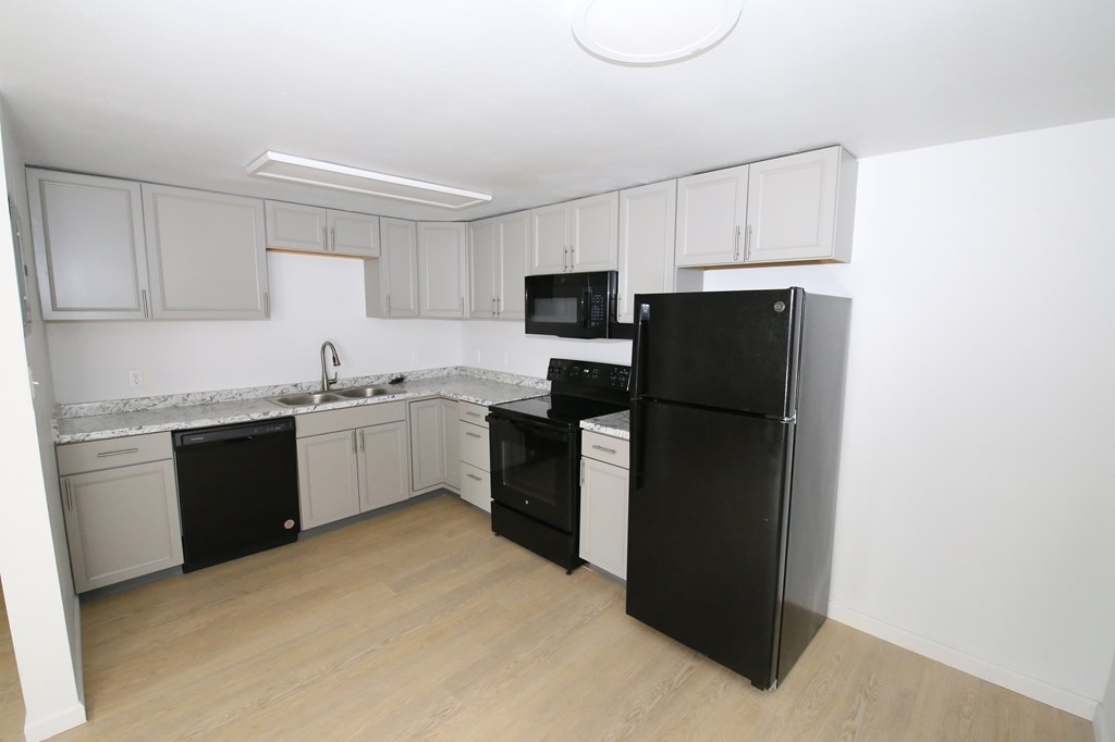 A kitchen with black appliances and white cabinets.