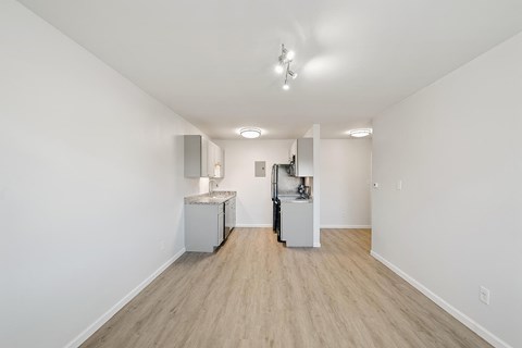 A white room with a kitchenette and a vacuum cleaner.