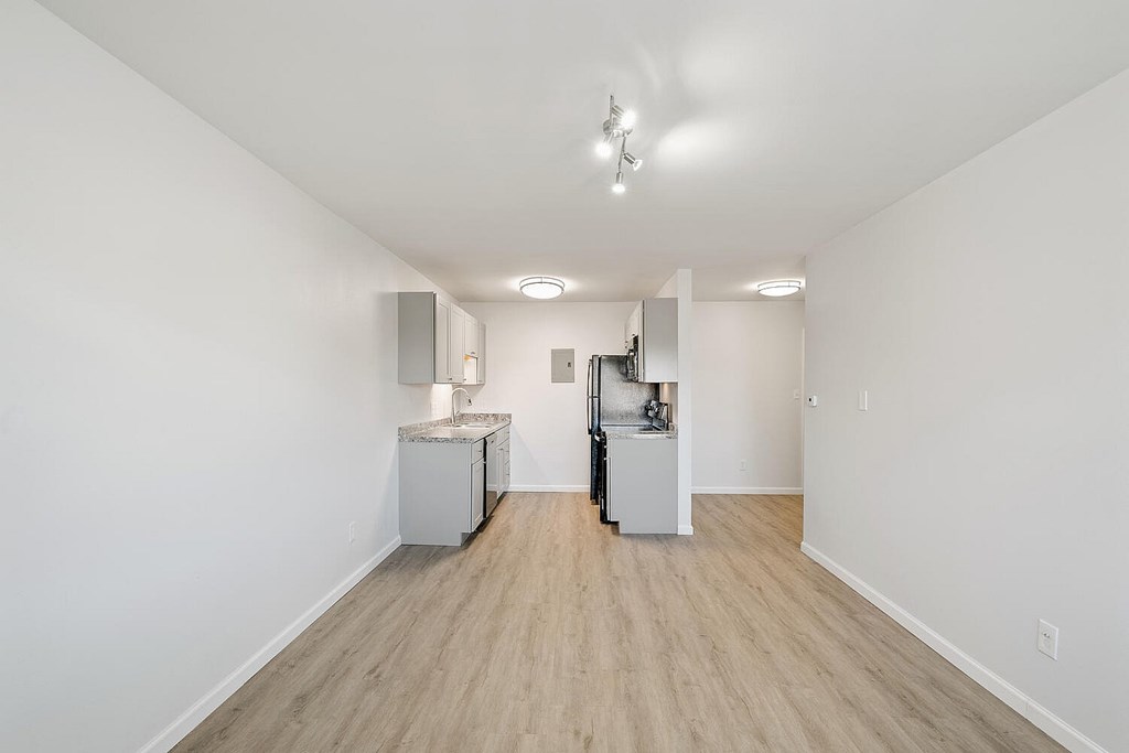 A white room with a kitchenette and a vacuum cleaner.
