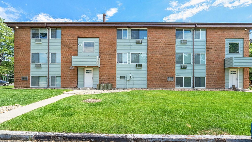 A red brick apartment building with a green lawn in front.