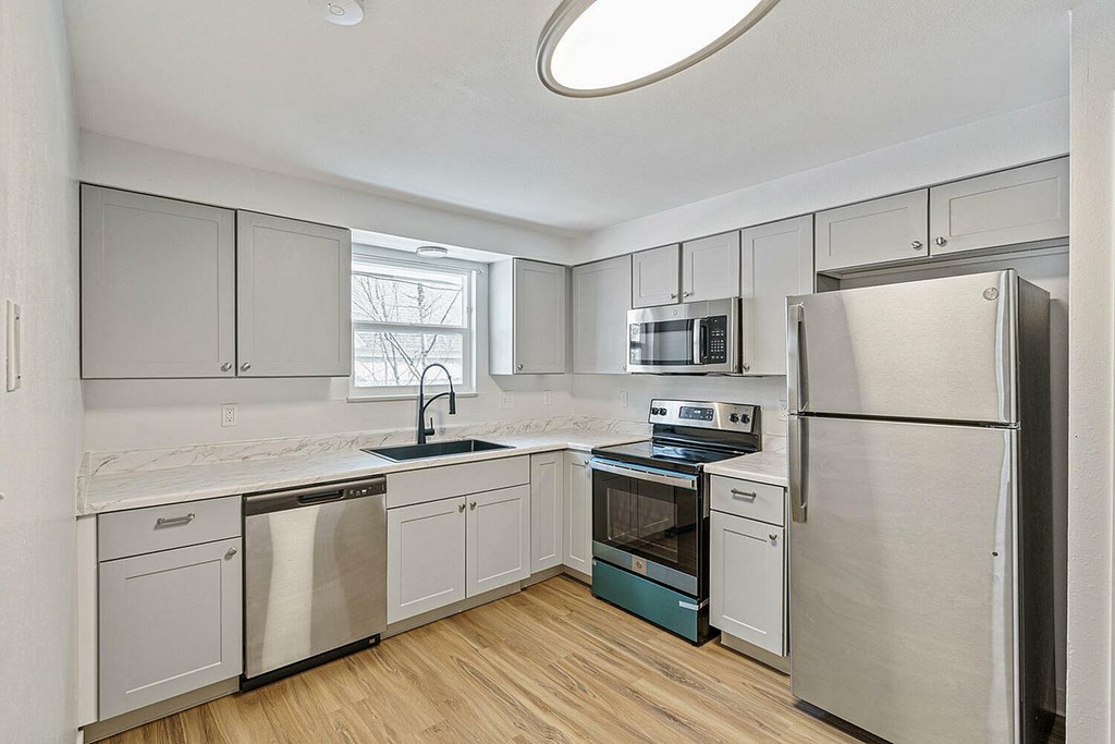 A kitchen with a refrigerator, sink, and oven.