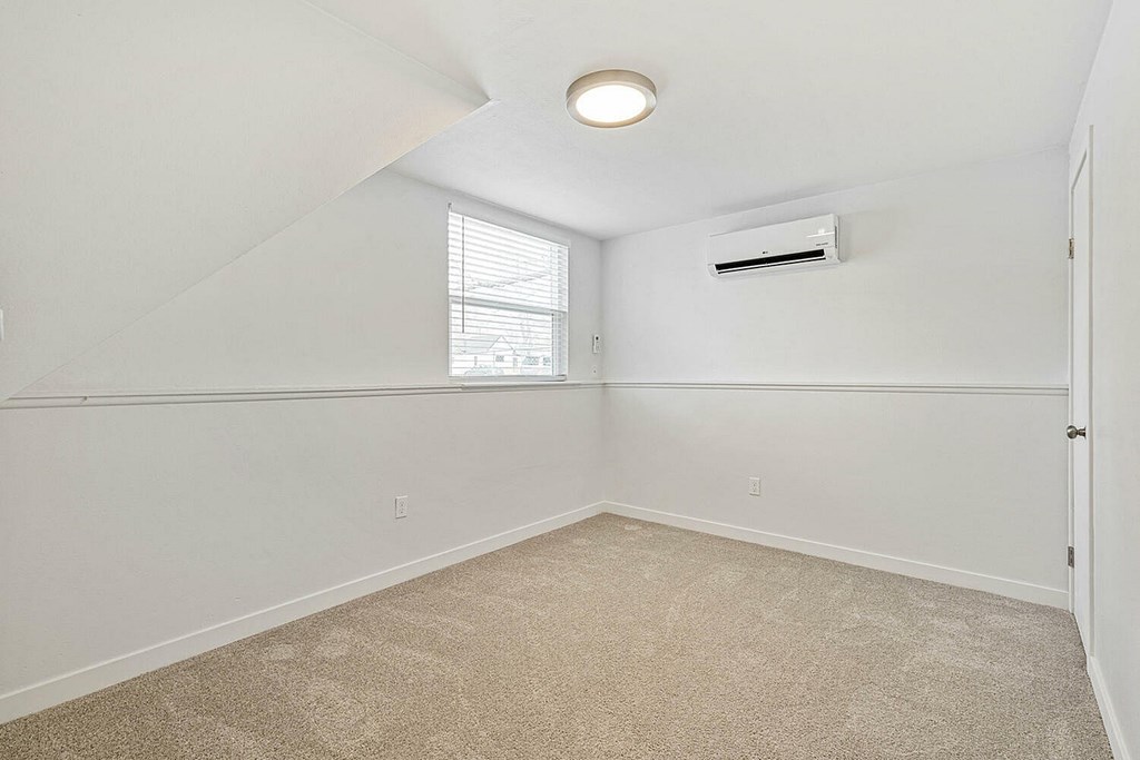 A room with a window and an air conditioner on the wall.