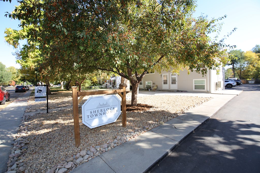 A sign that says Sherlock Town is in front of a tree.