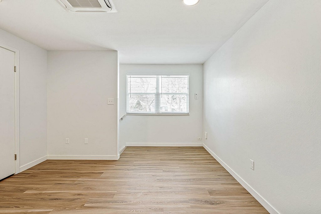 A room with wooden floors and a window with blinds.