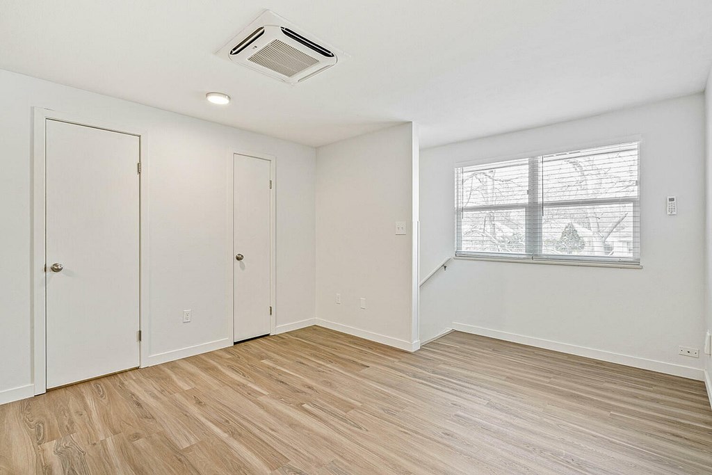 A room with a window and a wood floor.