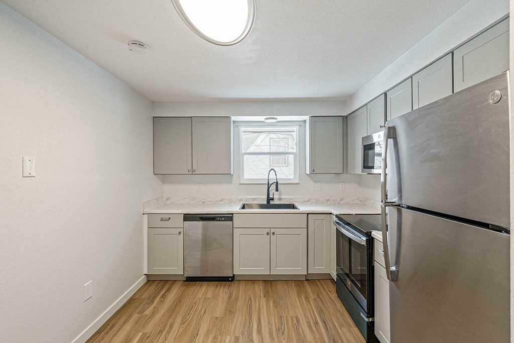 A kitchen with a refrigerator on the right side.