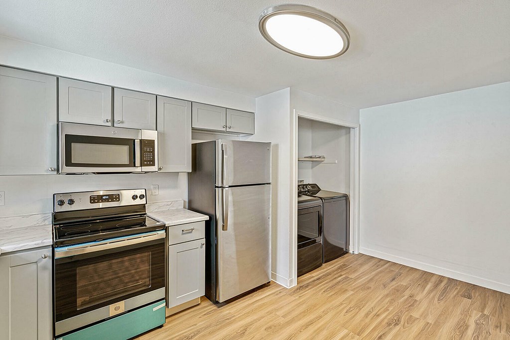 A kitchen with a stove top oven, microwave, and refrigerator.