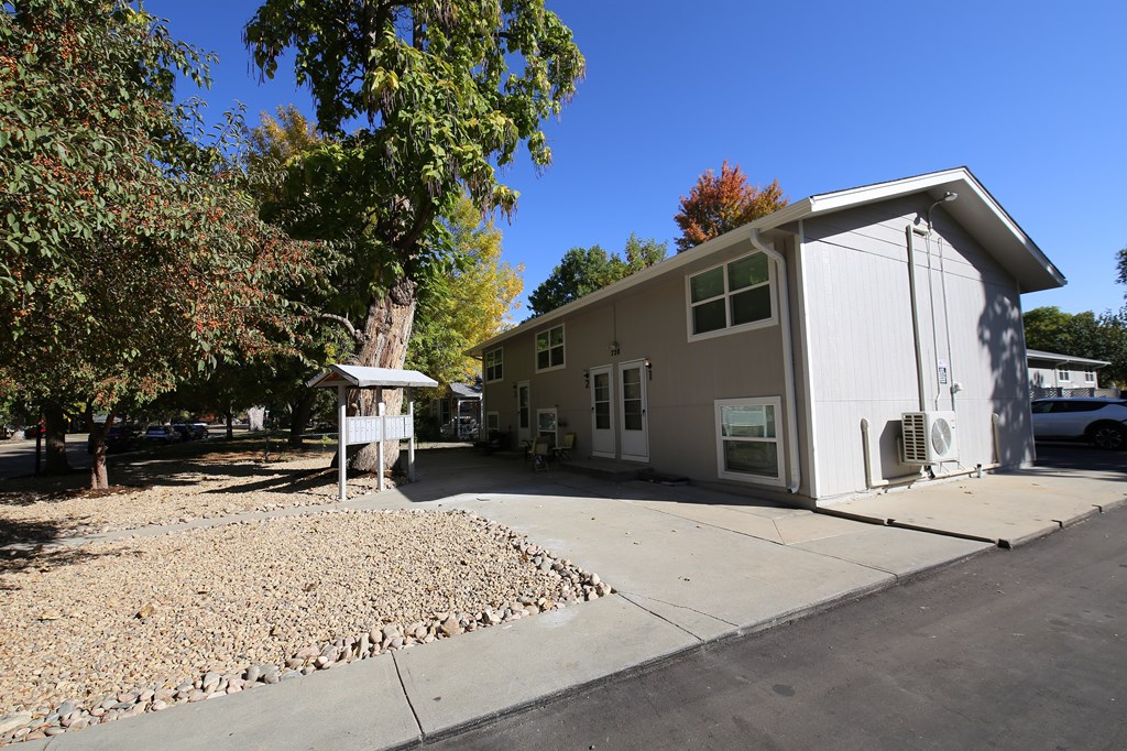 A small white house with a gravel driveway in front.