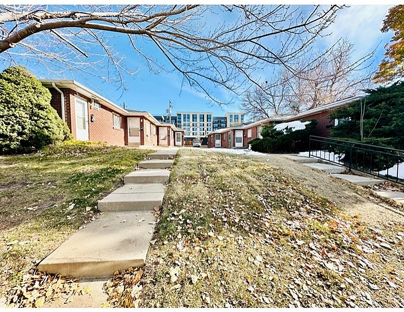 A row of houses with a sidewalk and fallen leaves.