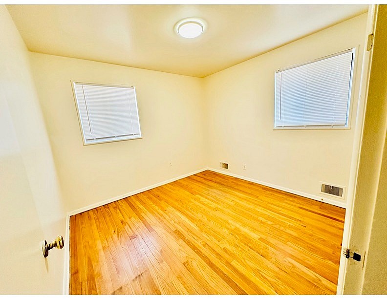 A room with wooden floors and two windows.