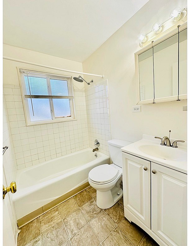 A white toilet sits next to a bathtub in a bathroom.