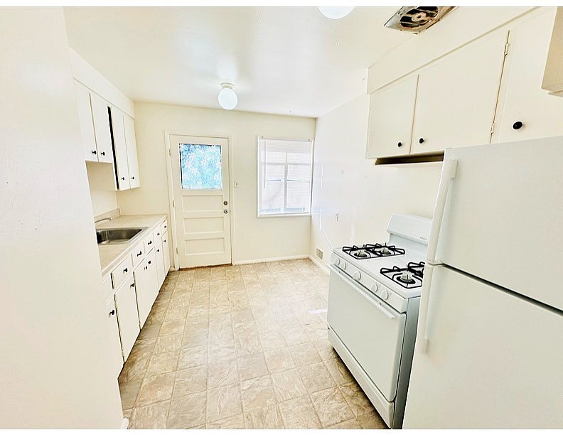 A kitchen with a white stove and cabinets.