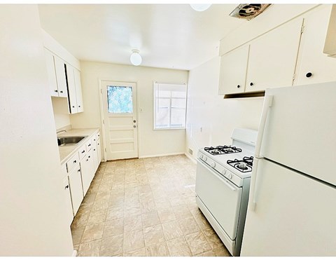 A kitchen with a white stove and cabinets.