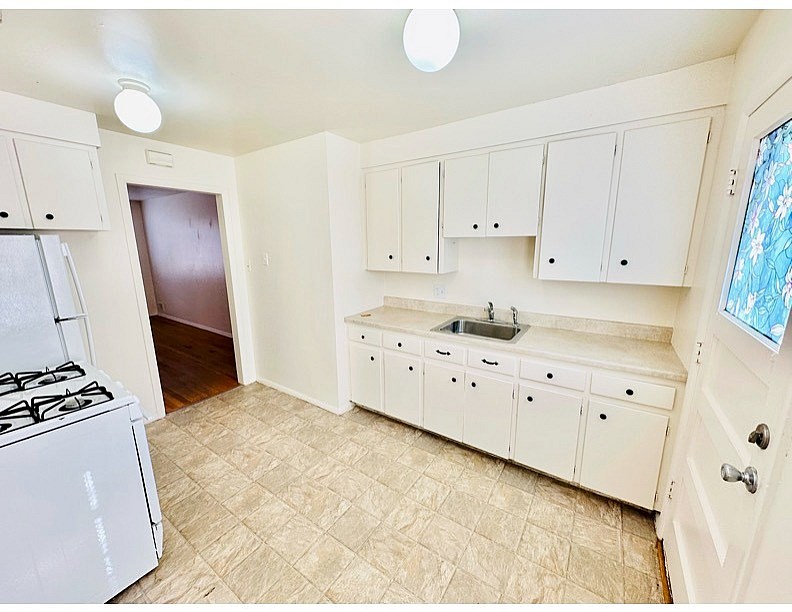 A kitchen with white cabinets and a tiled floor.