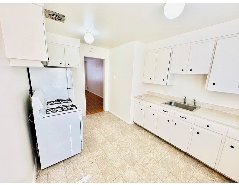 A kitchen with a white refrigerator and cabinets.