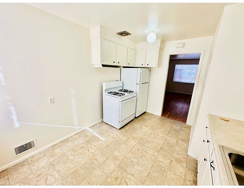 A kitchen with a white fridge and a tile floor.