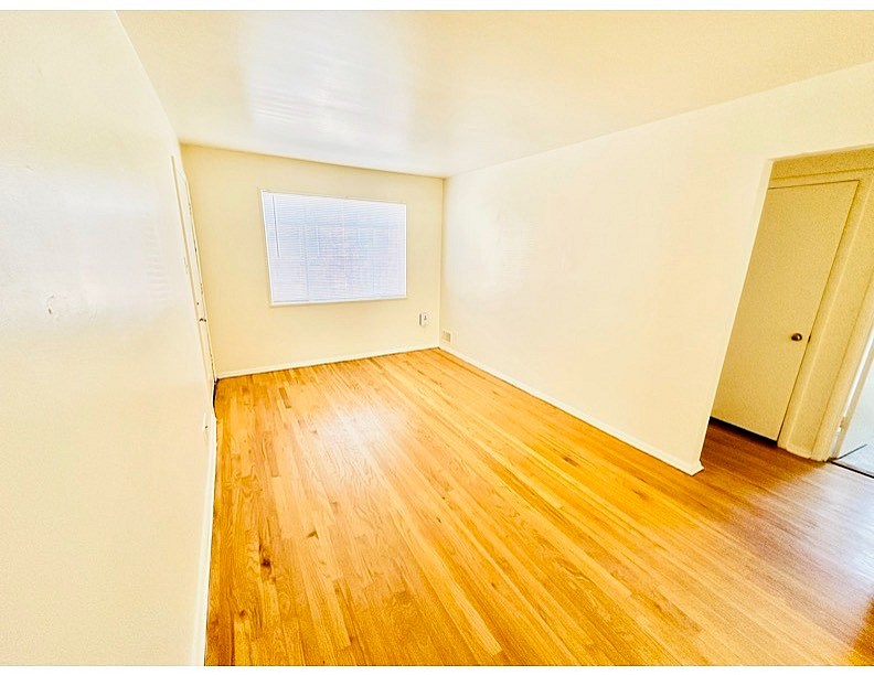 A room with wooden flooring and a white wall with a paper on it.