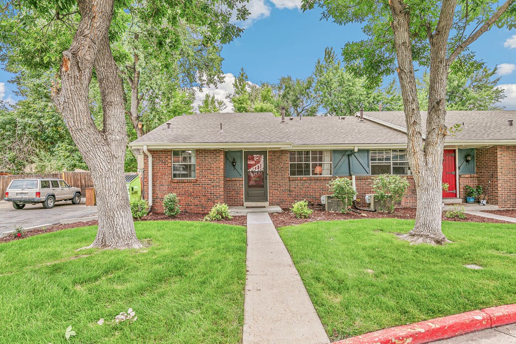 A red brick house with a red door and a red awning.
