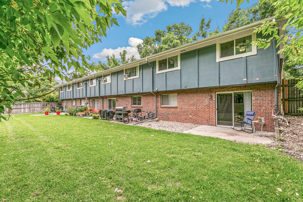A house with a green lawn and a blue sky in the background.