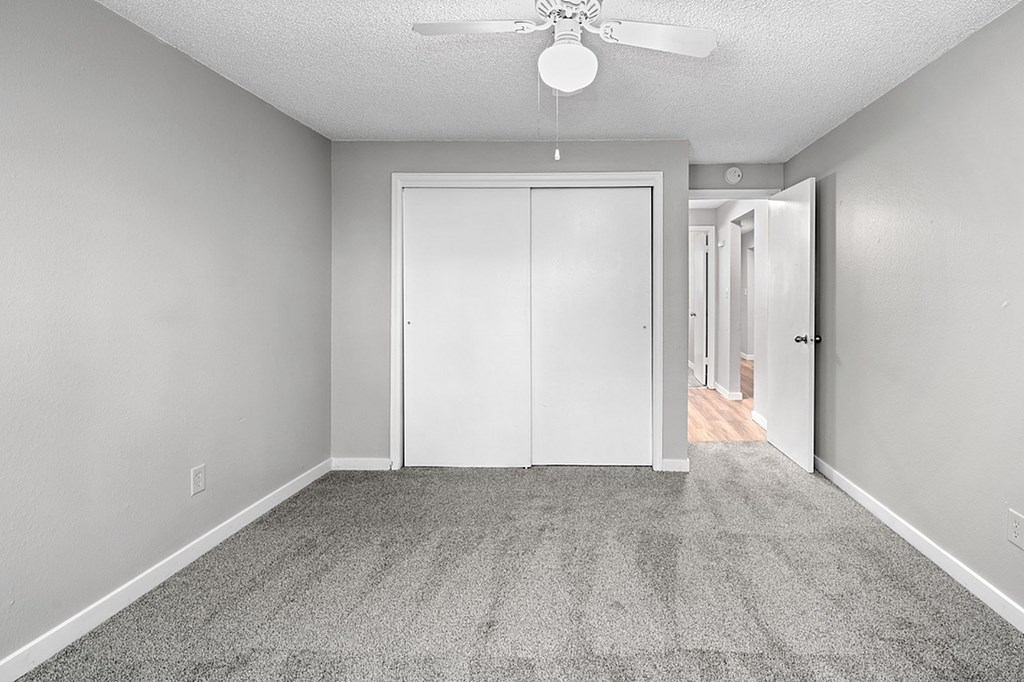 A room with a white door and a ceiling fan.