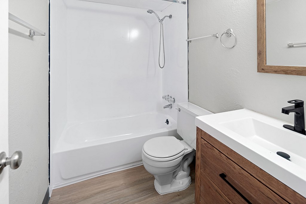 A white toilet sits next to a white bathtub in a bathroom.