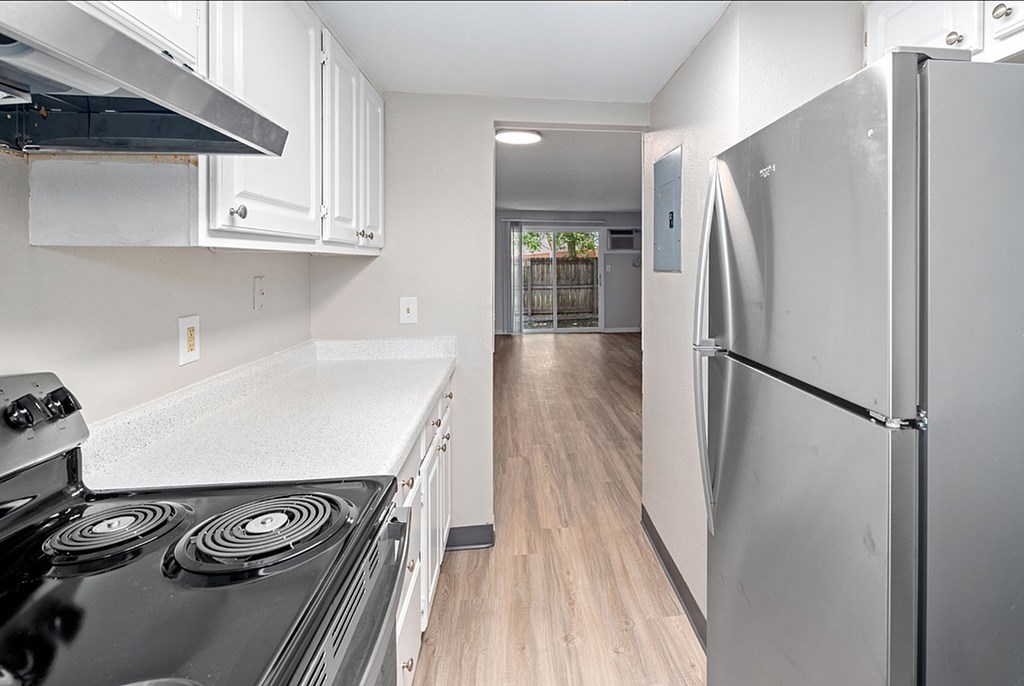 A kitchen with a black stove top oven and a silver refrigerator.
