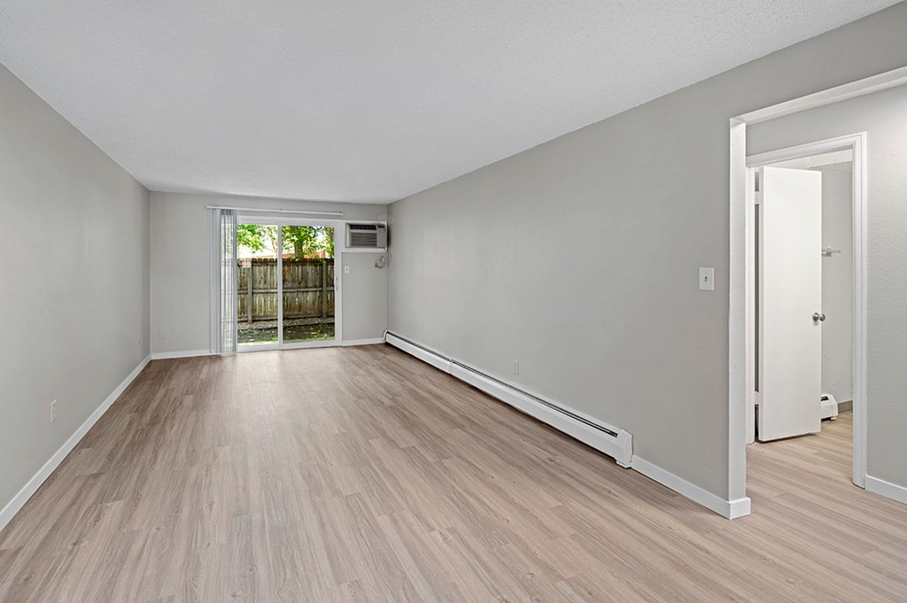 A room with light wood flooring and white walls.