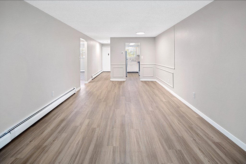 A long hallway with wood flooring and white walls.