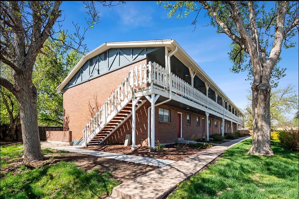 A red brick building with a white porch and stairs.