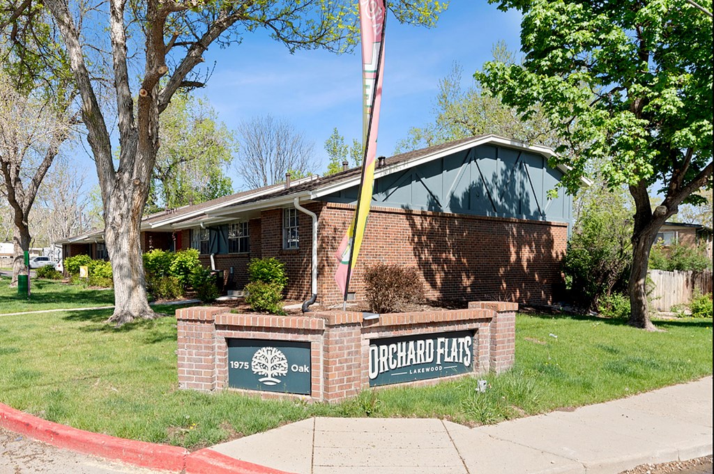 A brick building with a sign that says Orchard Flats in front of it.